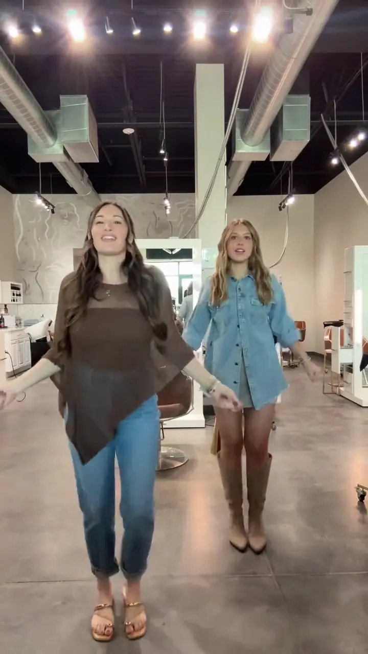 The Babydoll dance AI trend template: two friends doing the two-step in a bright hair salon, vertical 9:16